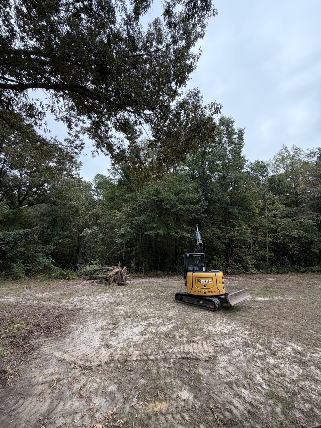 Bratchco mini excavator clearing a house lot in Haskell, Arkansas — stumps pulled and brush being removed